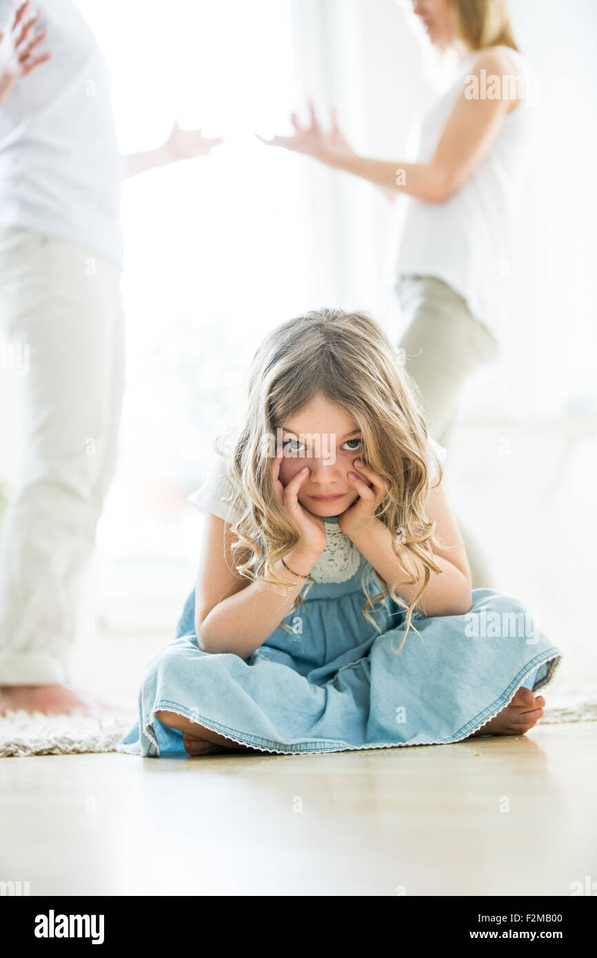 Petite fille assise en tailleur sur le plancher parents se disputer en arriere plan Photo Stock Alamy
