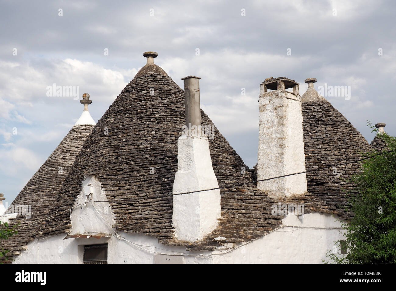 Mur en pierre, cheminées et d'un toit conique trullo maison. Banque D'Images