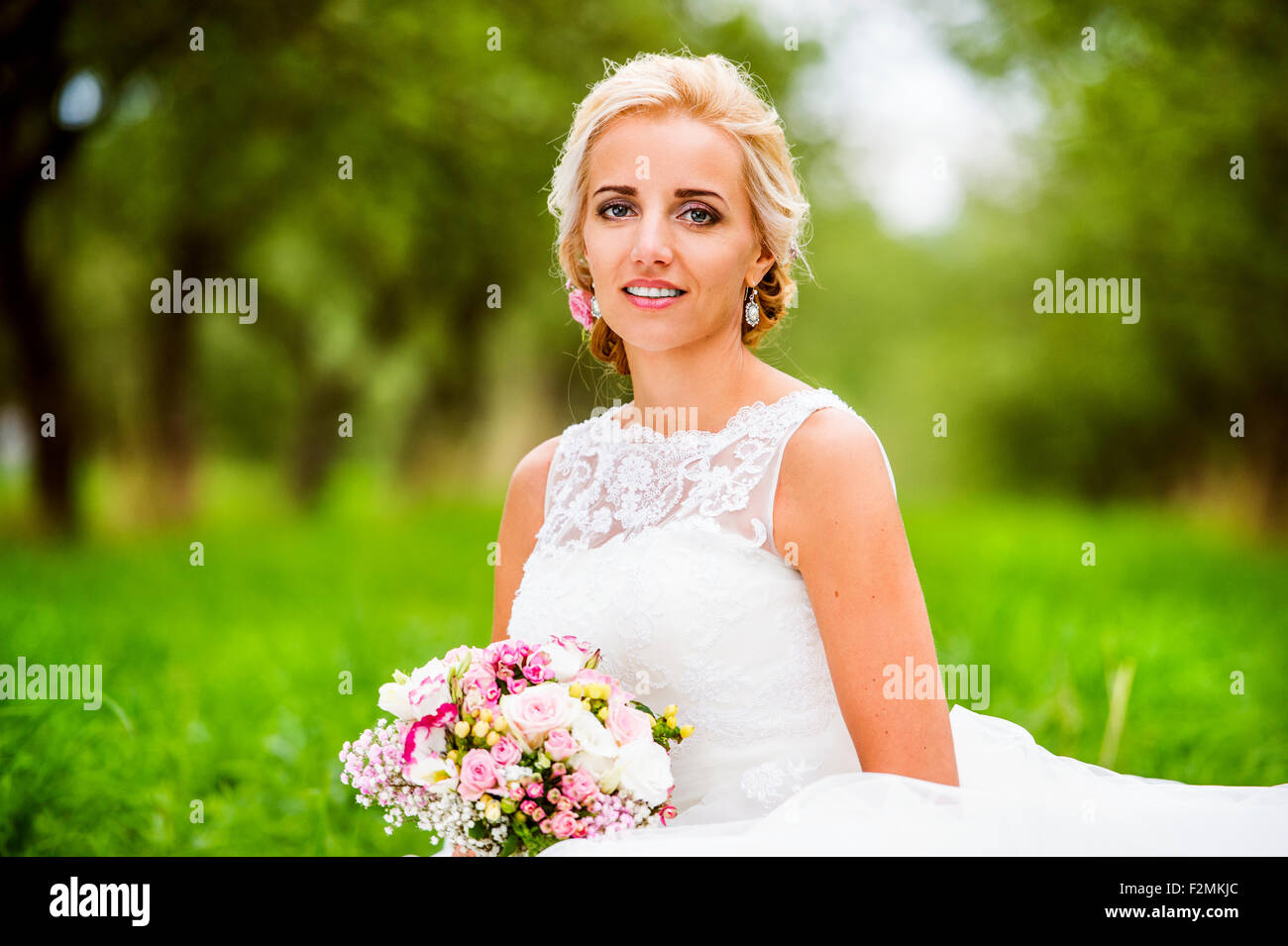 Belle jeune femme en robe de mariage assis dans l'herbe Banque D'Images