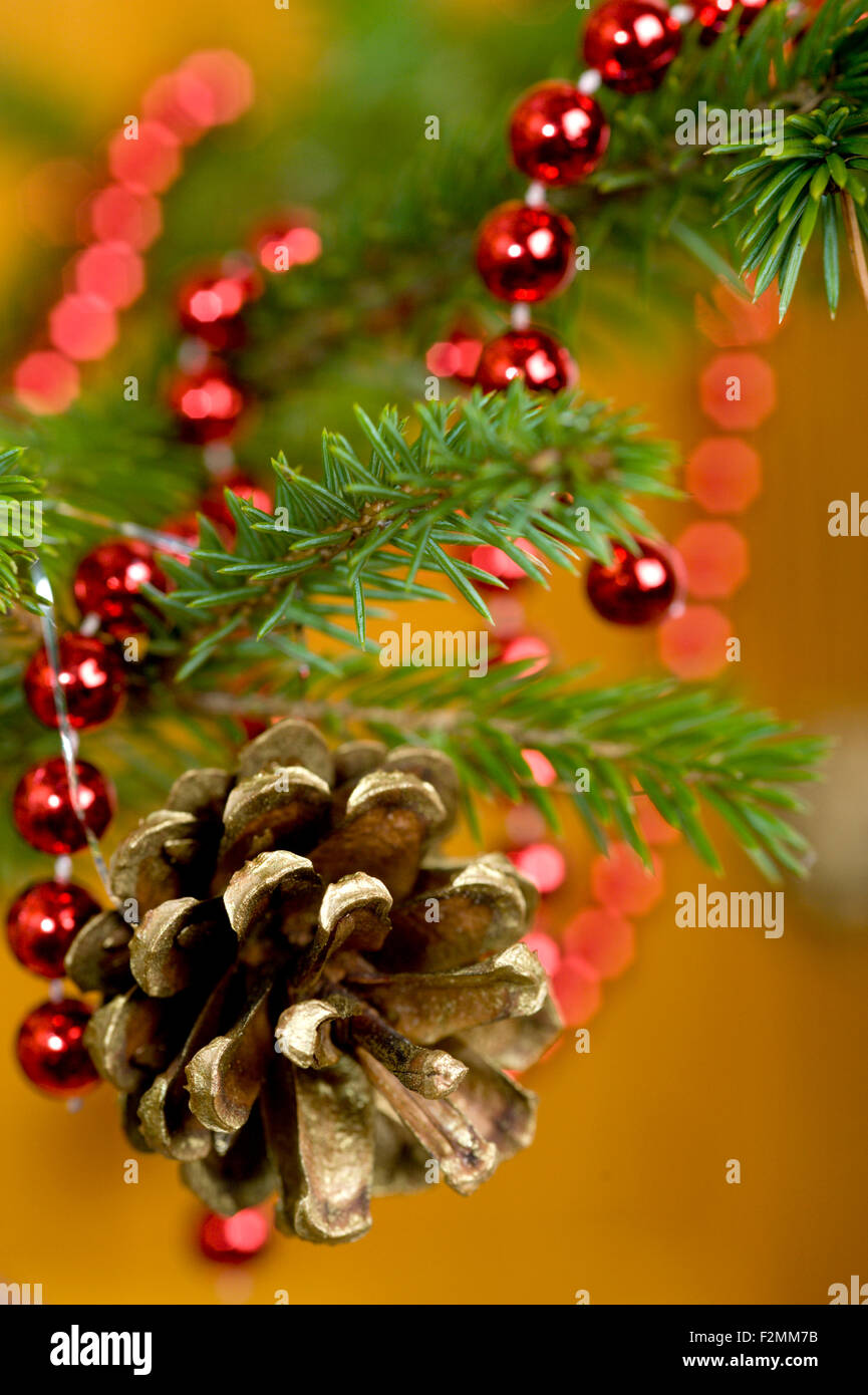 Une décoration d'arbre de Noël traditionnel à l'aide d'un cône de pin pulvérisée et certains lametta ainsi qu'une chaîne de beeds rouge brillant Banque D'Images