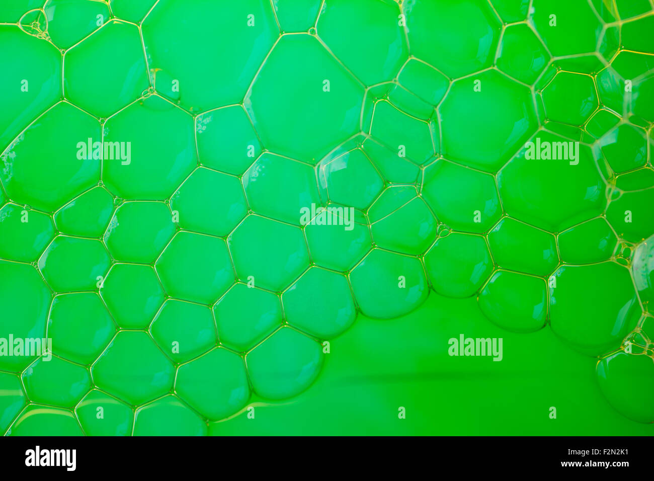 Gros plan extrême de l'eau savonneuse créer de belles motif dans lime green Banque D'Images