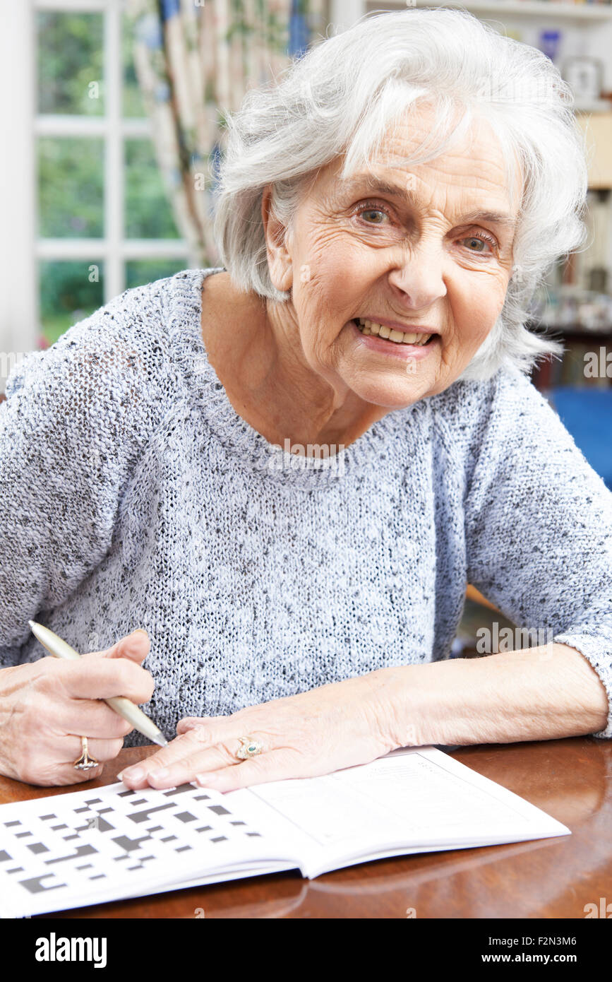 Senior Woman Relaxing With Mots croisés à la maison Banque D'Images