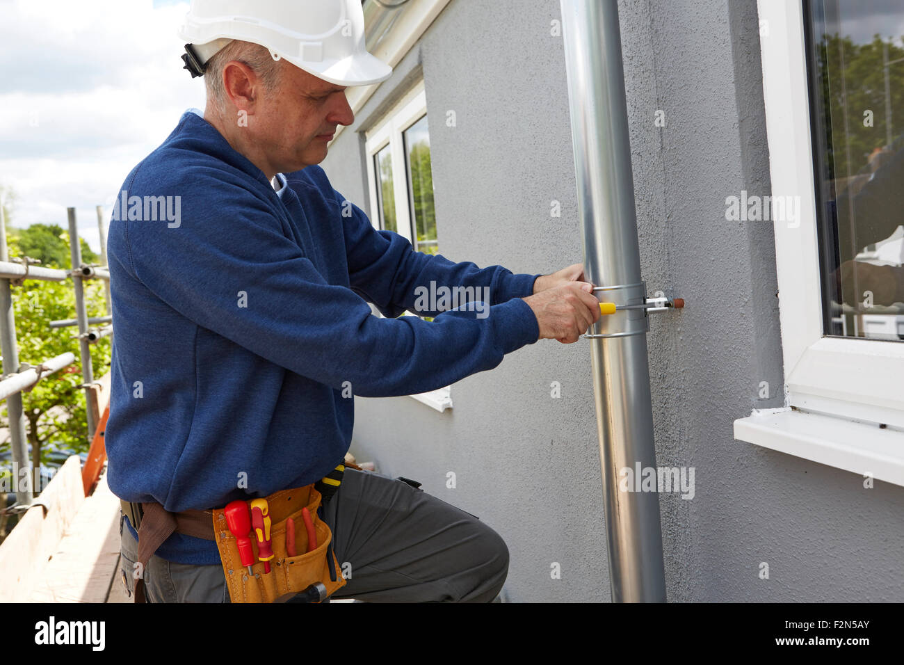 Workman remplacement des gouttières sur façade de maison Banque D'Images