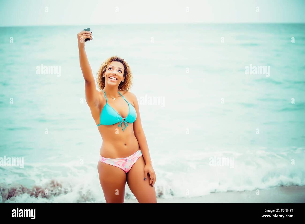 Mixed Race teenager prenant en selfies bikini on beach Banque D'Images