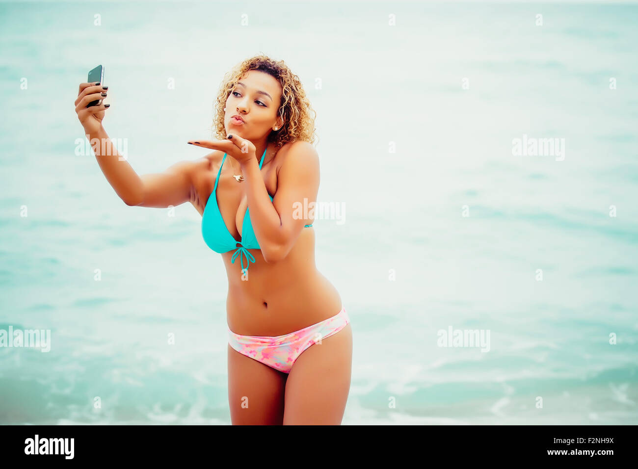 Mixed Race teenager prenant en selfies bikini on beach Banque D'Images