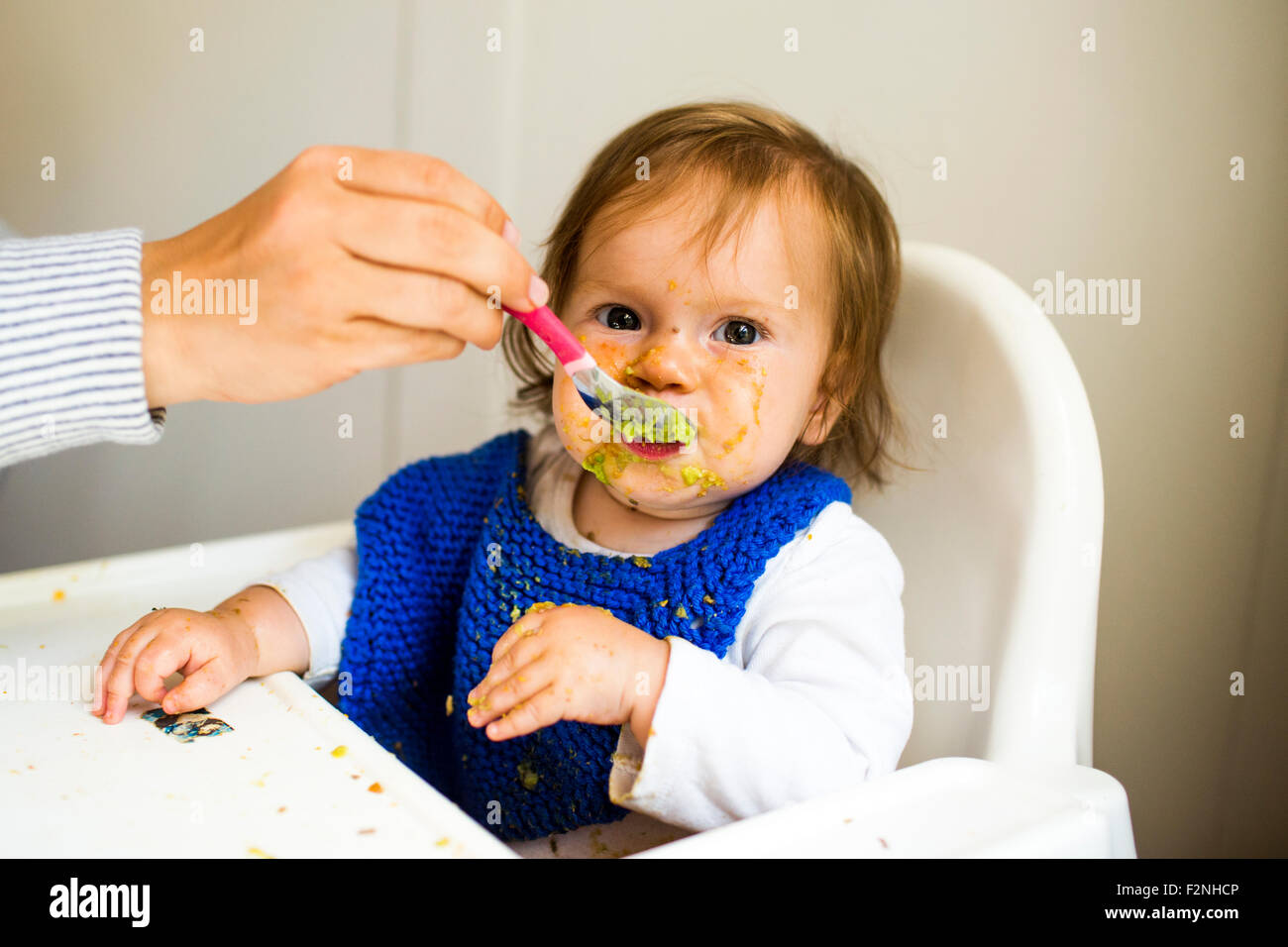 Mère nourrir bébé fille dans une chaise haute Banque D'Images