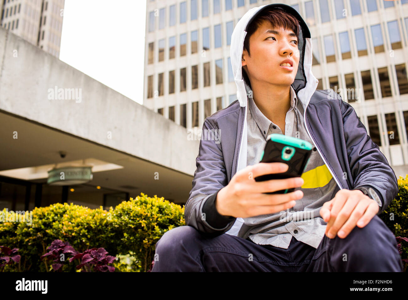 Asian man using cell phone in city Banque D'Images
