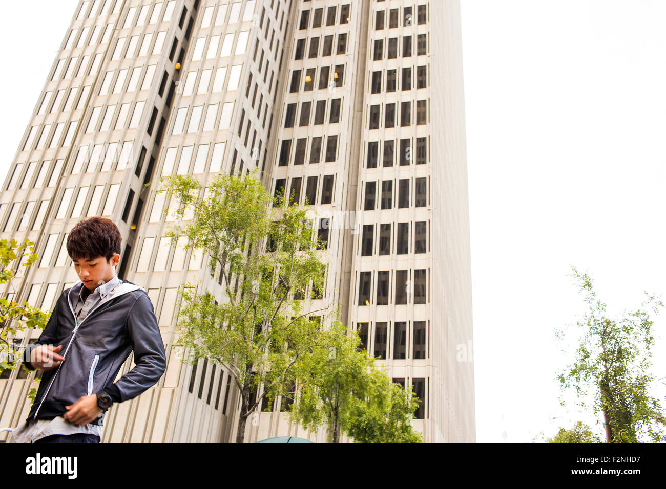 Asian man standing près de gratte-ciel urbain Banque D'Images