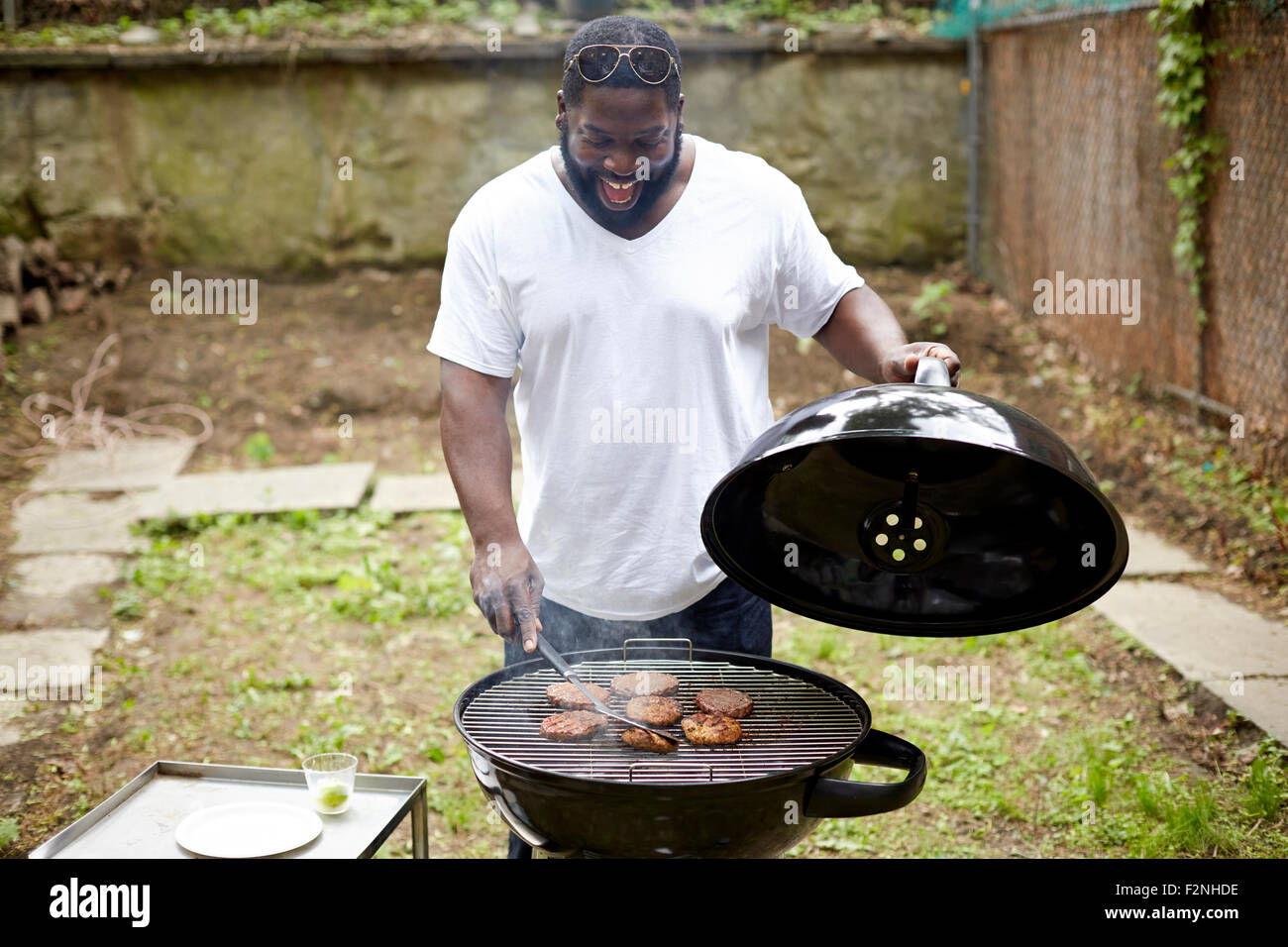 Black man grilling des hamburgers dans un barbecue Banque D'Images