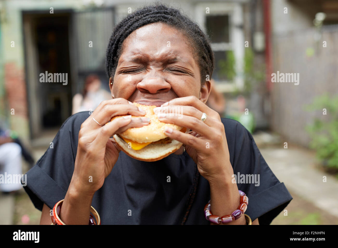 African American Woman eating at backyard barbecue Banque D'Images