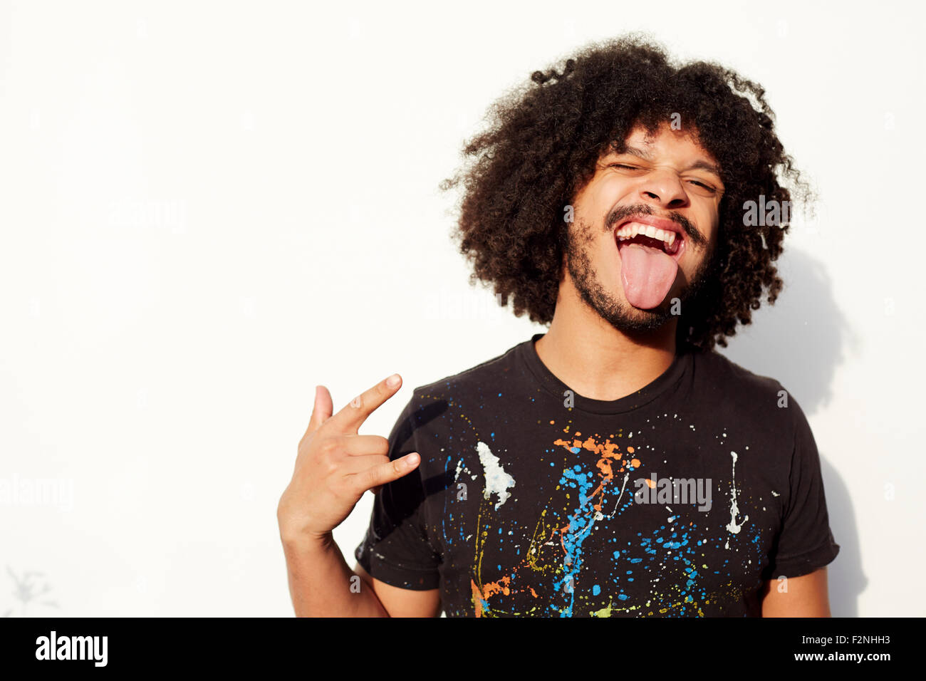 Mixed Race man making a face et rock-sur hand gesture Banque D'Images