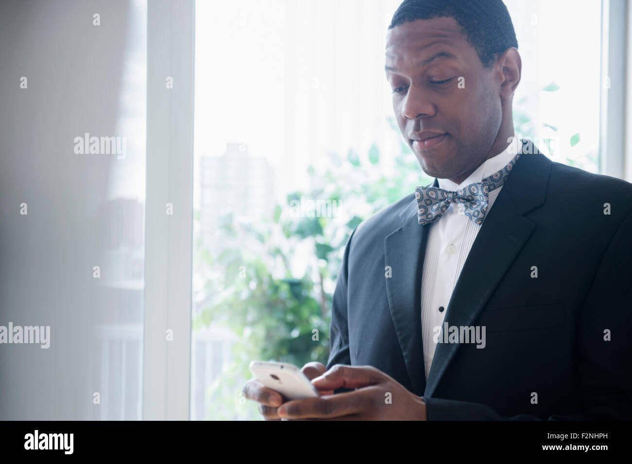 Groom in tuxedo using cell phone Banque D'Images