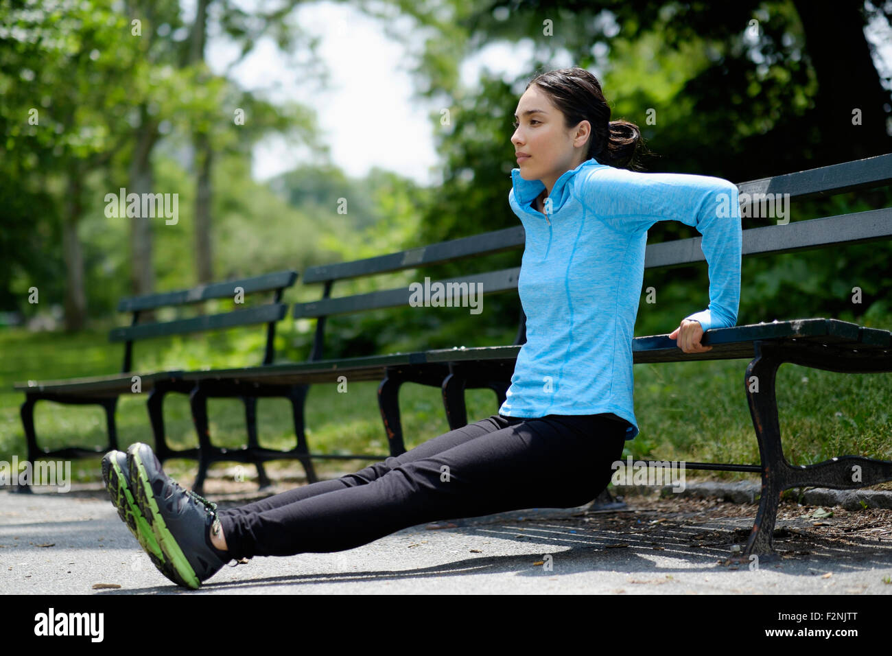 Hispanic woman faisant push-ups on park bench Banque D'Images