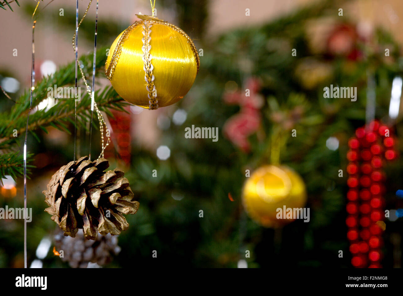 Colorée et traditionnelle décoration d'arbre de Noël composé d'une jolie boule soyeuse jaune un cône de pin lametta et perles Banque D'Images