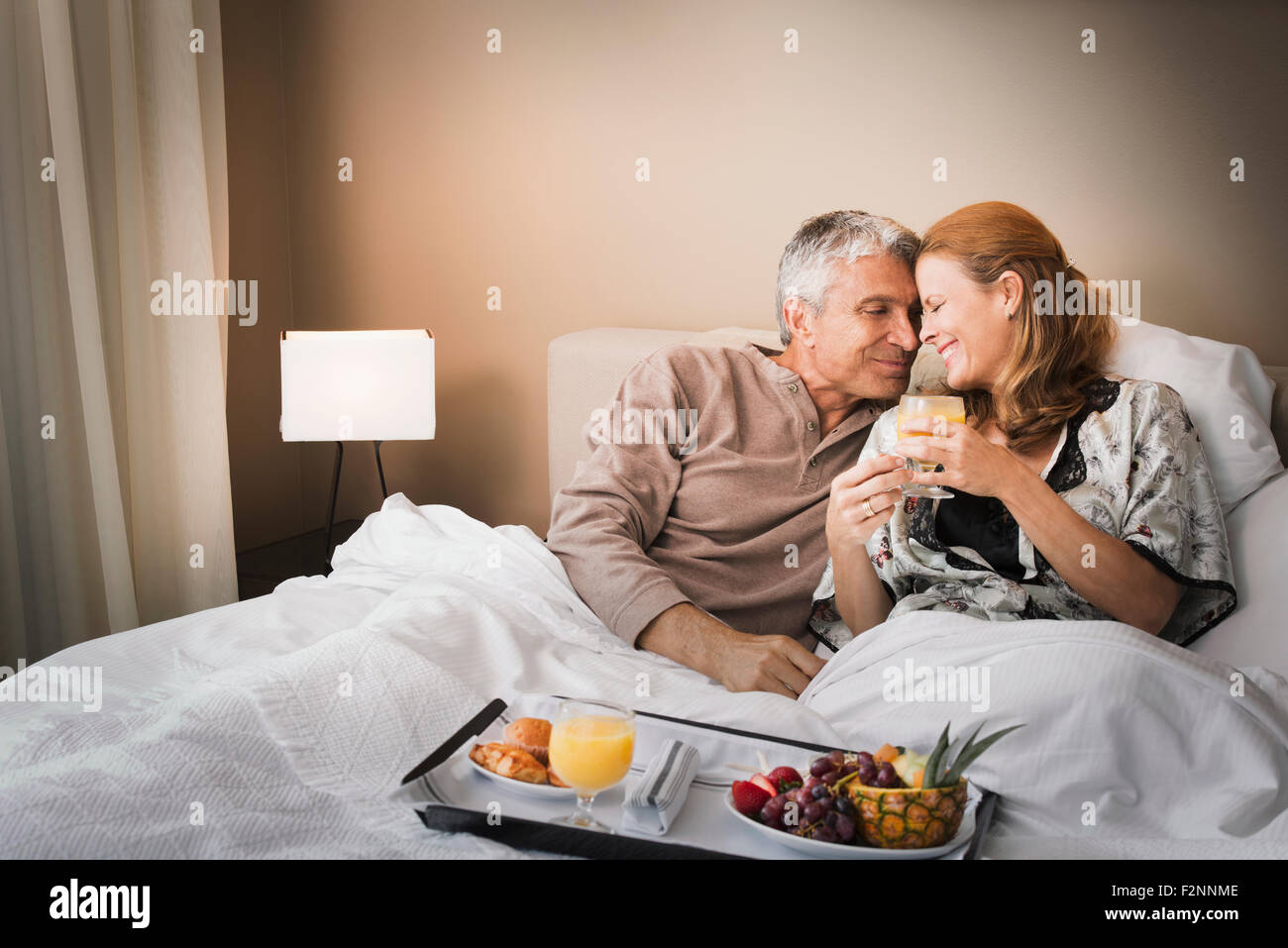 Smiling couple having breakfast in bed Banque D'Images