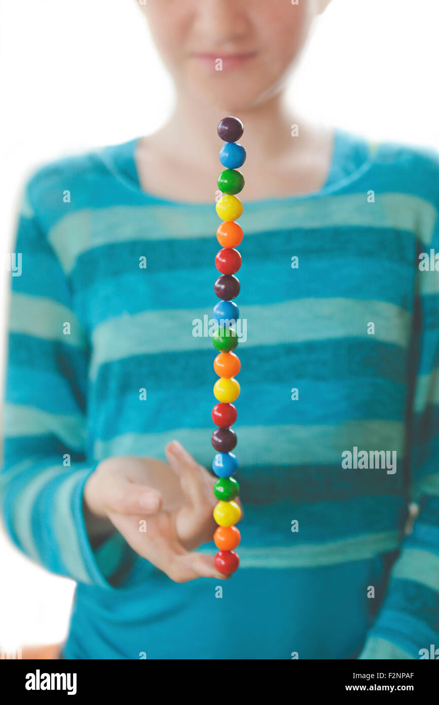 Caucasian girl balancing bonbons arc-en-ciel sur le doigt Banque D'Images