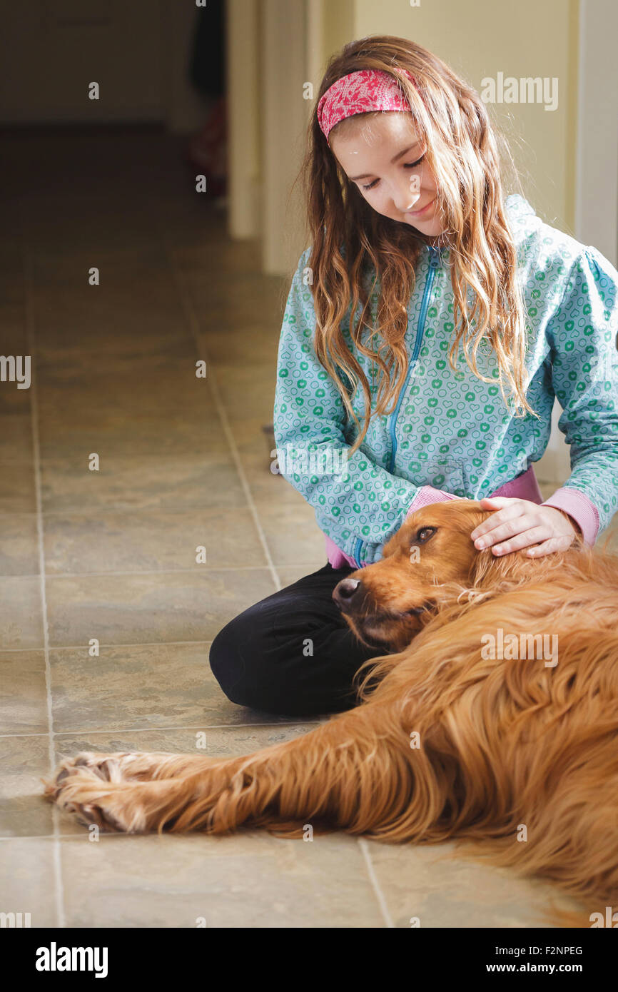 Caucasian girl petting dog on floor Banque D'Images