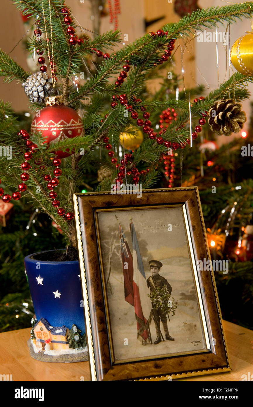 Carte postale nostalgique de la première guerre mondiale et encadrée, debout devant un arbre de Noël traditionnel décoré Banque D'Images