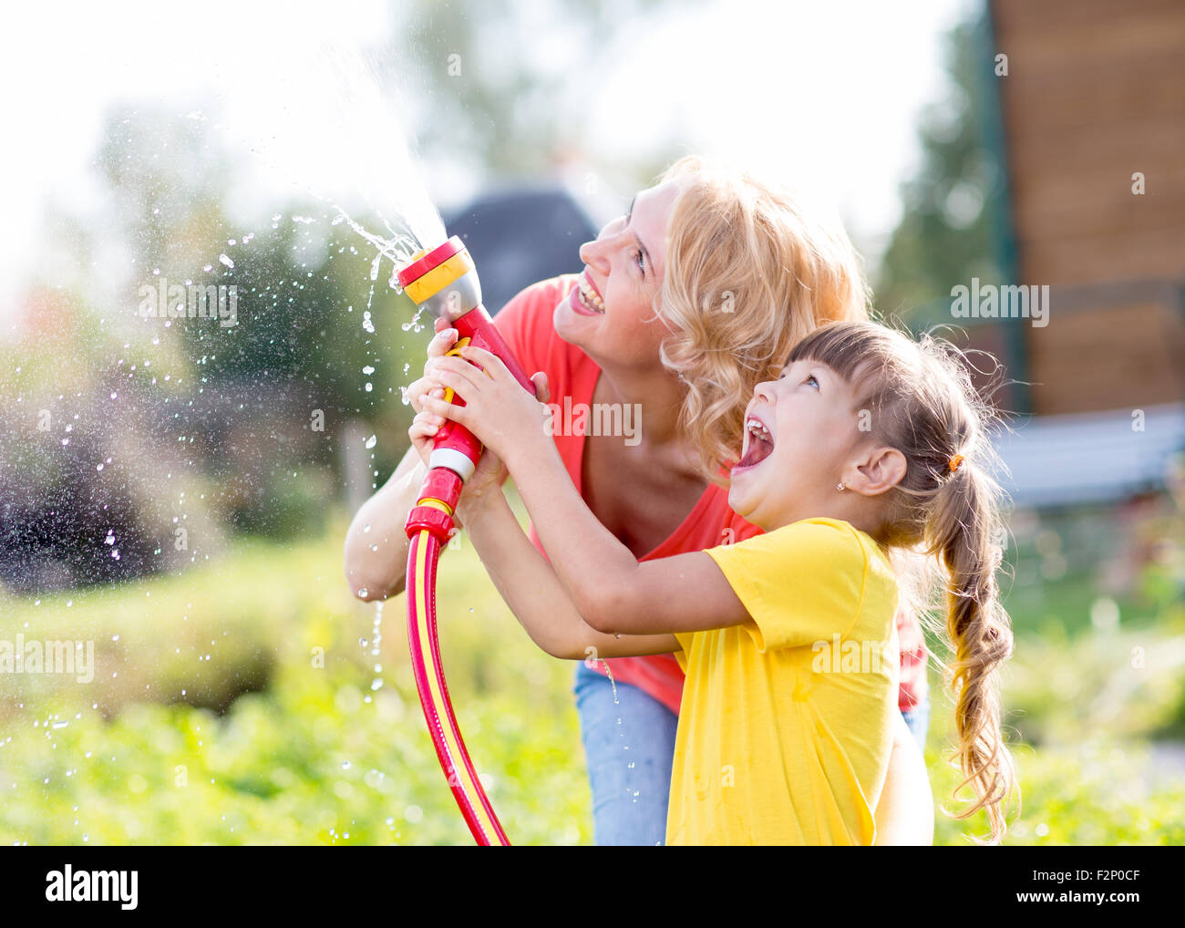 Heureuse femme et enfant fille de l'eau dans le jardin intérieur Banque D'Images