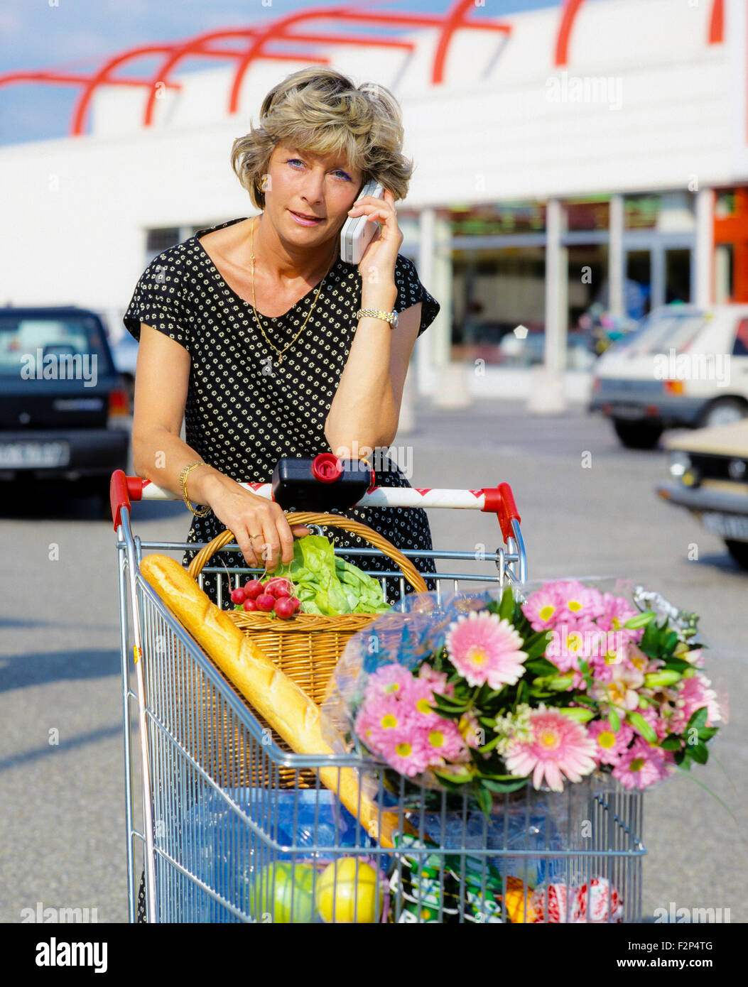 Femme mature de parler sur son téléphone cellulaire en at supermarket Banque D'Images