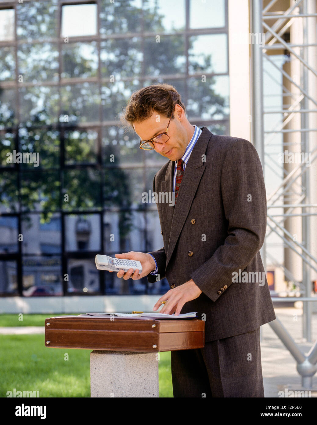 Businessman avec un téléphone cellulaire et la date livre en face de bâtiment de bureaux France Europe Banque D'Images