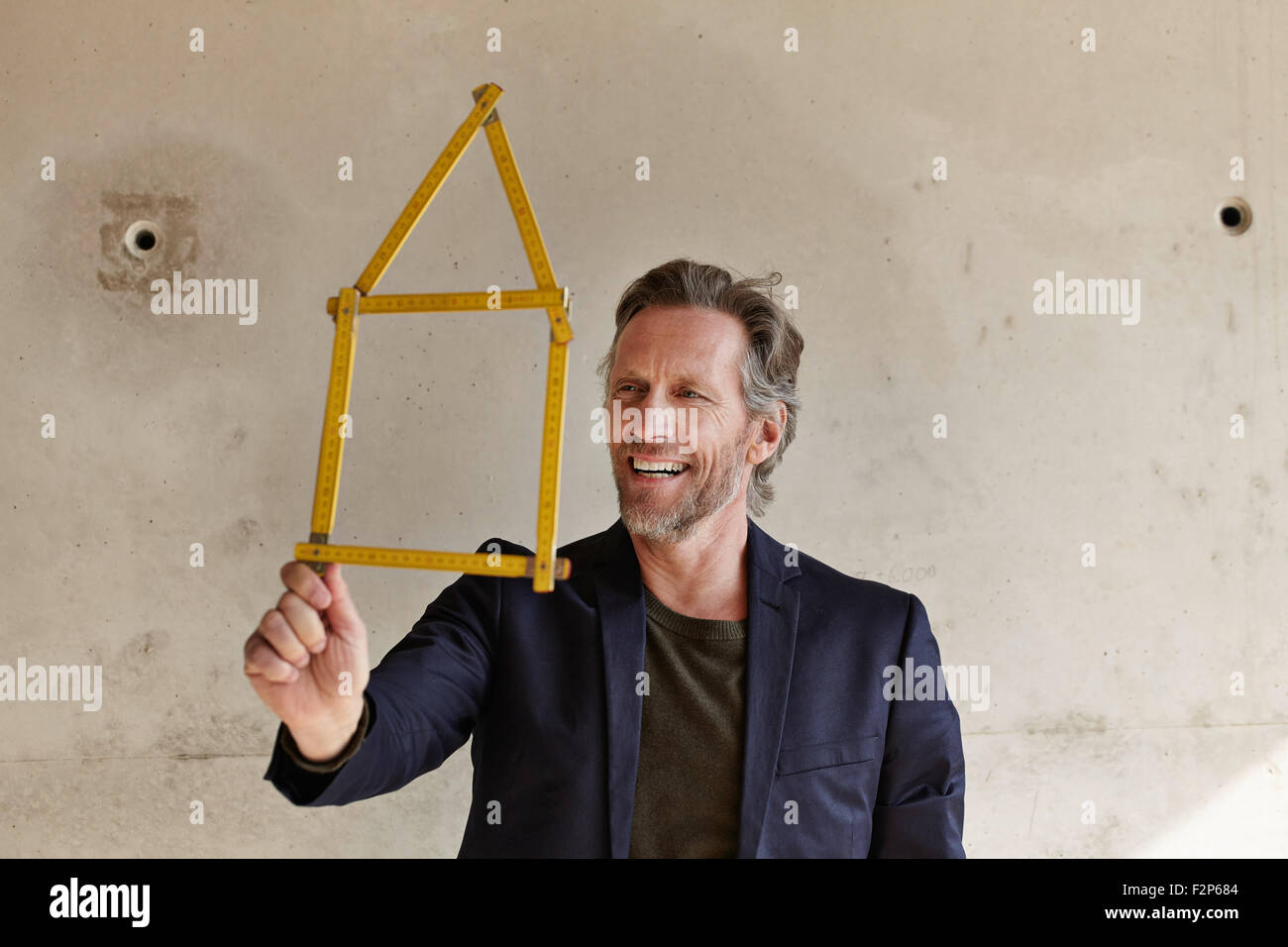 Smiling man holding mètre de poche en forme de maison Banque D'Images