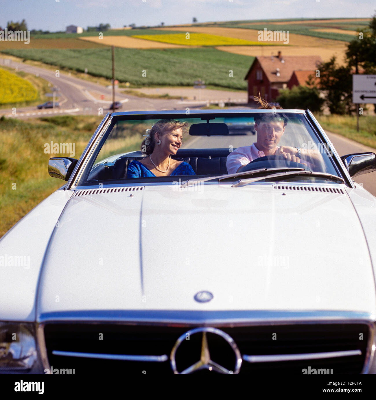 Couple au volant d'une voiture décapotable Mercedes on country road, Alsace, France Europe Banque D'Images