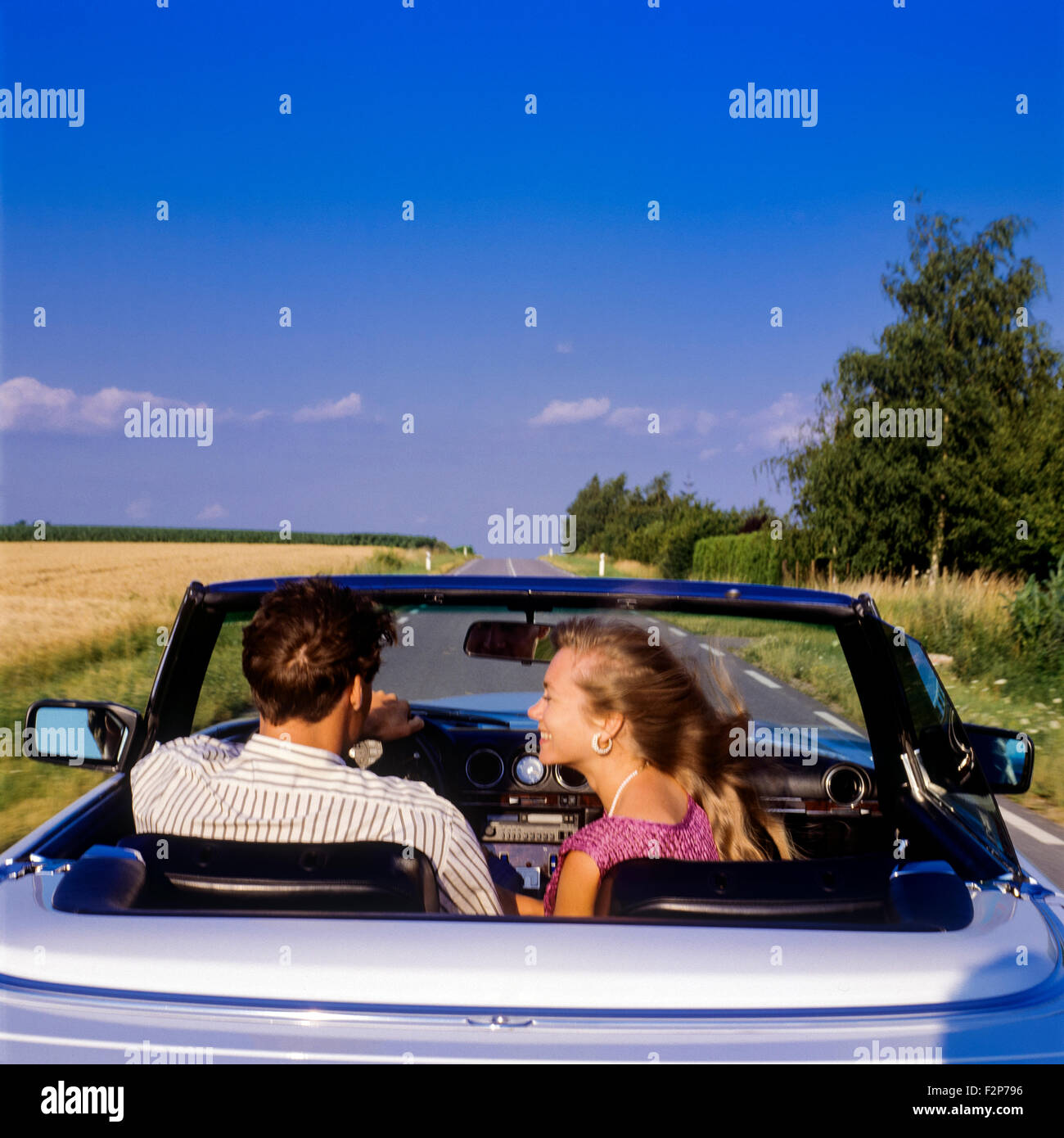 Vue arrière d'un couple au volant d'une Mercedes décapotable voiture sur une route de campagne, Alsace, France Banque D'Images