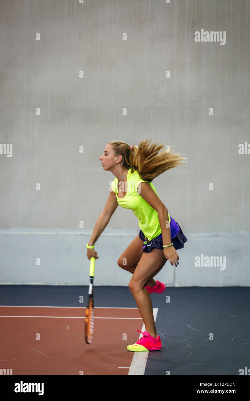 Jeune femme jouant au tennis dans un centre de tennis intérieur Banque D'Images