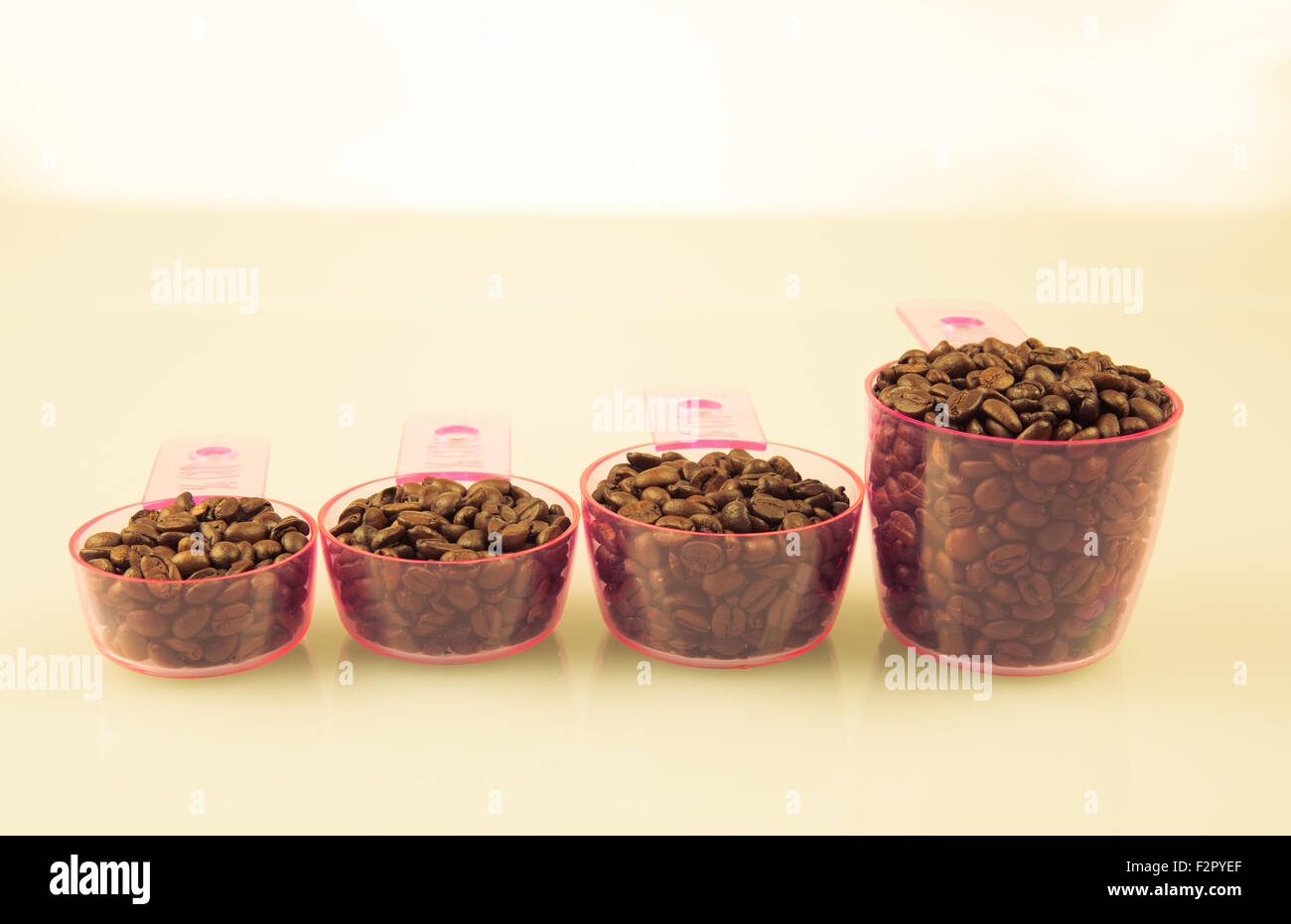 Grains de café dans les tasses à mesurer de diverses tailles. Banque D'Images