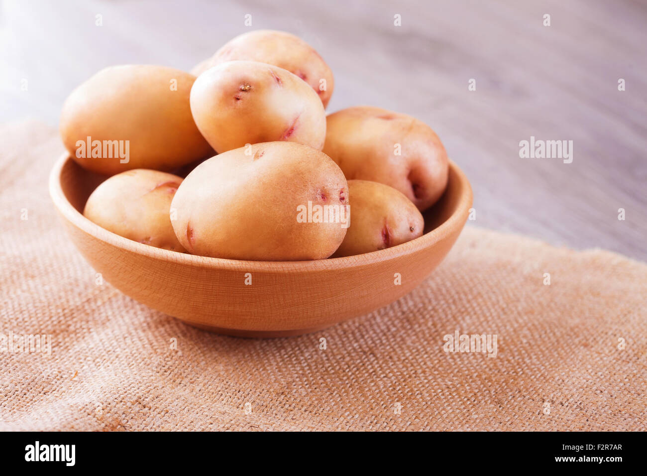Les pommes de terre crues dans un bol sur fond de bois, vue en gros Banque D'Images