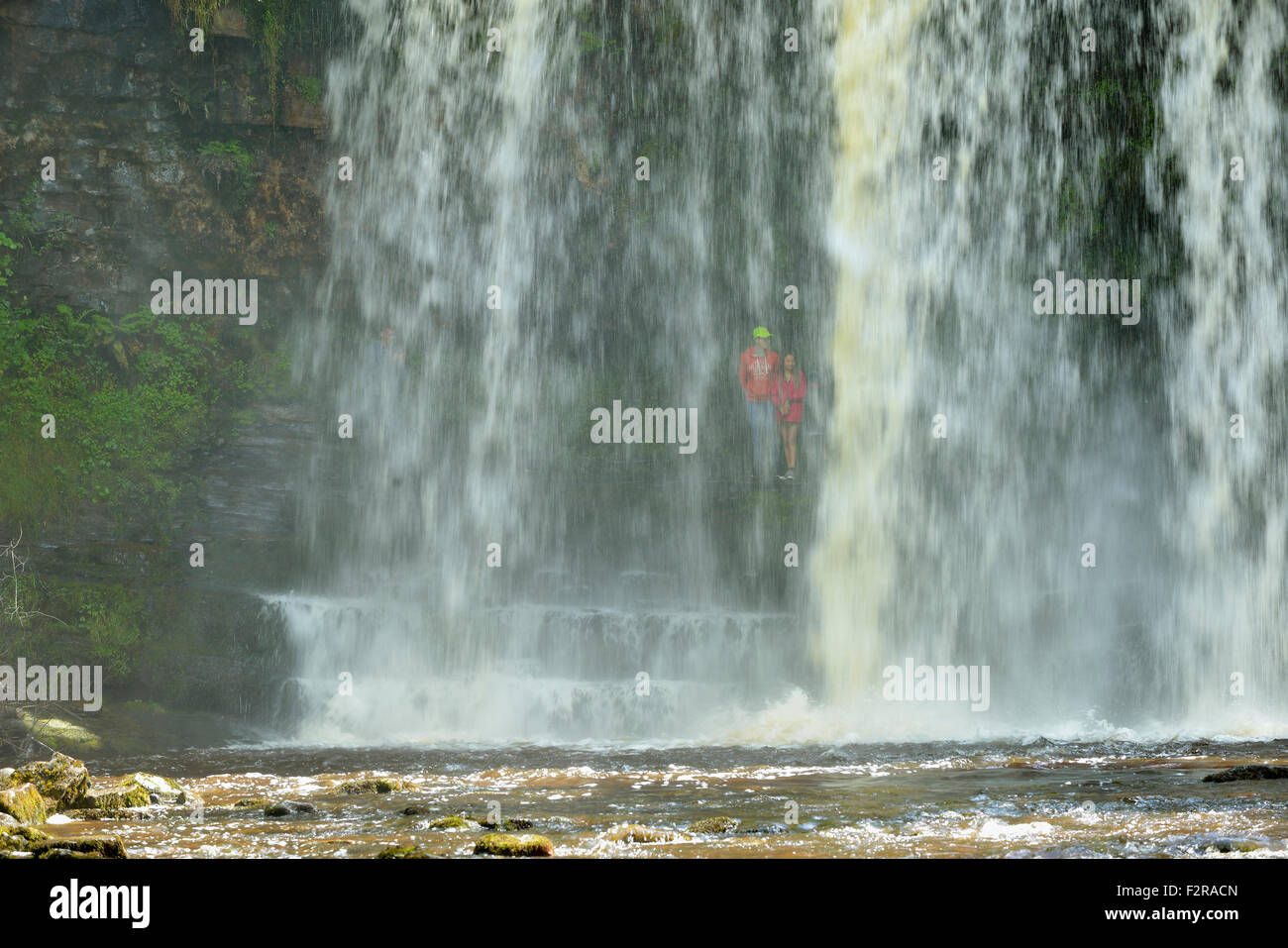 Jeune couple derrière Sgwd yr Eira Cascade ; Afon Hepste River Brecon Beacons, Pays de Galles Banque D'Images