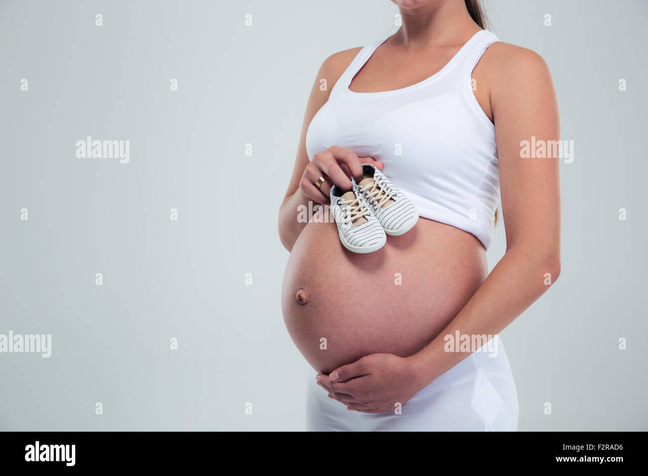 Closeup portrait of a pregnant woman holding a baby booties isolé sur fond blanc Banque D'Images
