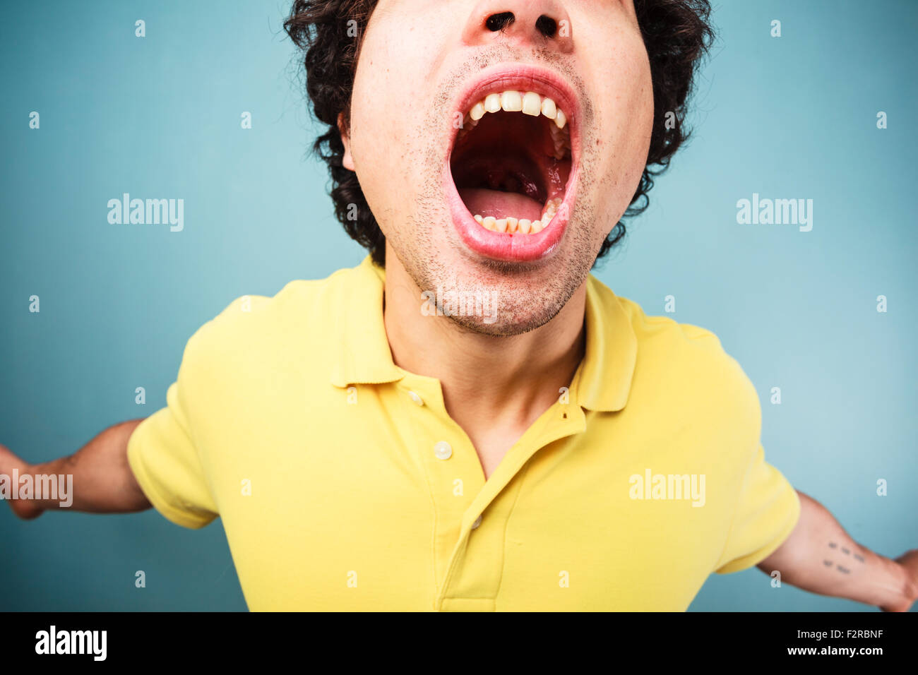 Jeune homme hurle avec la bouche grande ouverte Banque D'Images