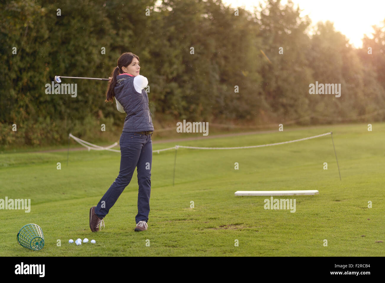 Golfeuse debout sur la gamme de conduite sur une journée en fin d'après-midi, debout dans la position de finition Banque D'Images