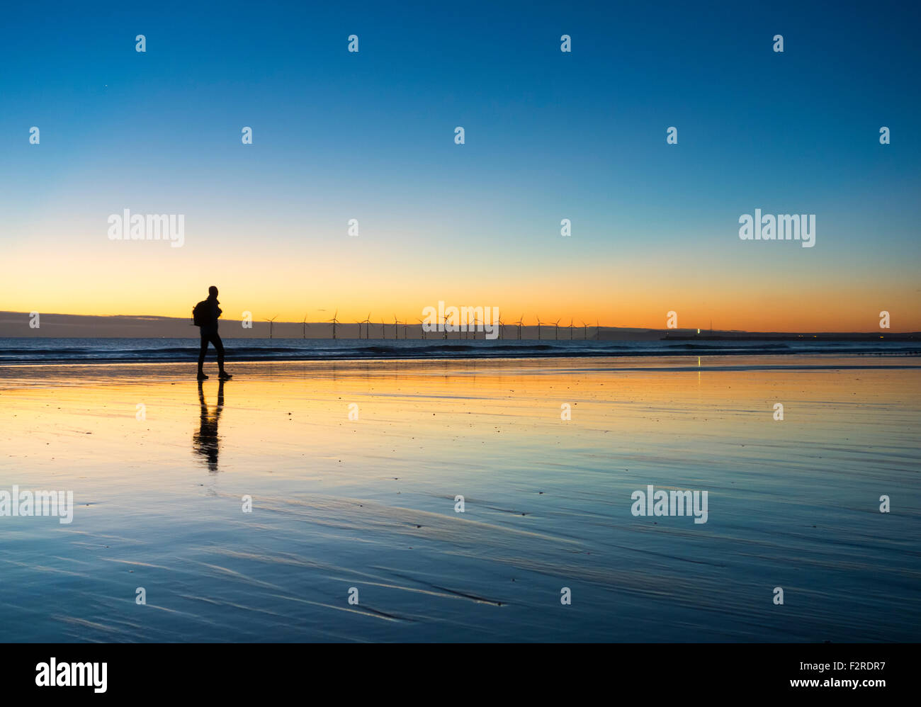 Un marcheur sur Seaton Carew beach au lever du soleil, qui établit, sur 55km le long du chemin de la côte de l'Angleterre. Seaton Carew, Angleterre. UK Banque D'Images