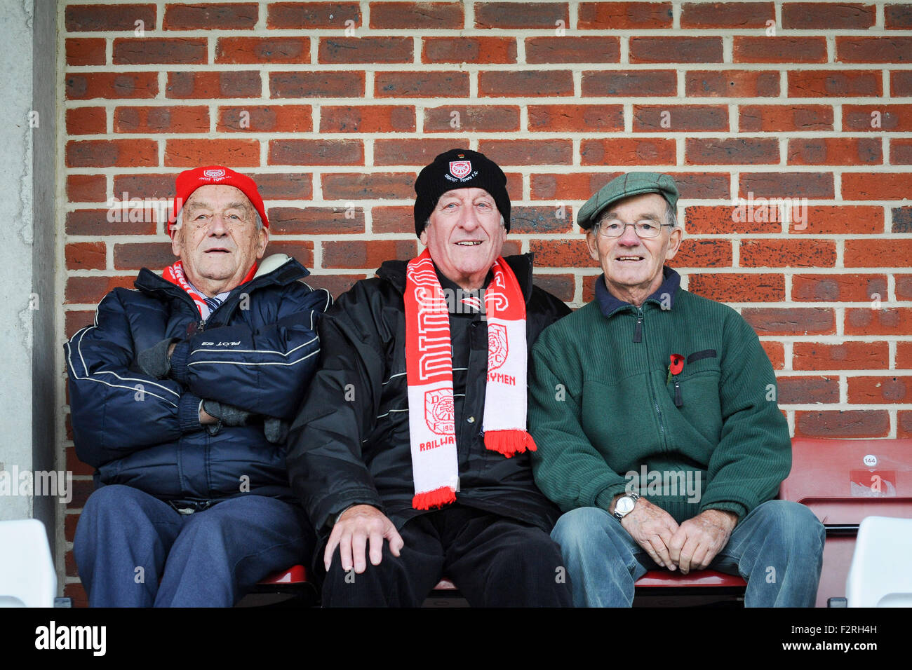 3 football supporters portant des chapeaux et foulards regarder un match Banque D'Images