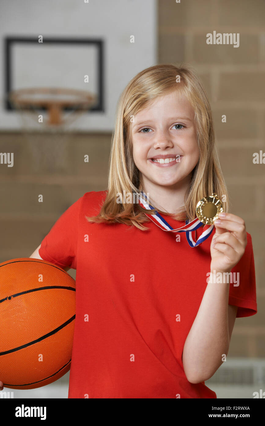 Girl Holding Basket-ball et de médaille en gymnase de l'école Banque D'Images