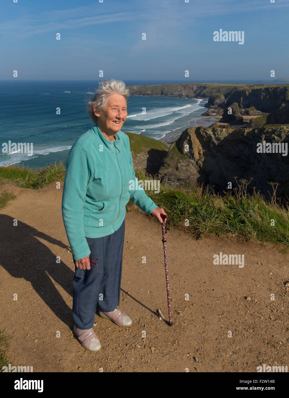 Vieille dame actif pensionné avec bâton de marche par belle côte scene Bedruthan Steps Cornwall uk Banque D'Images