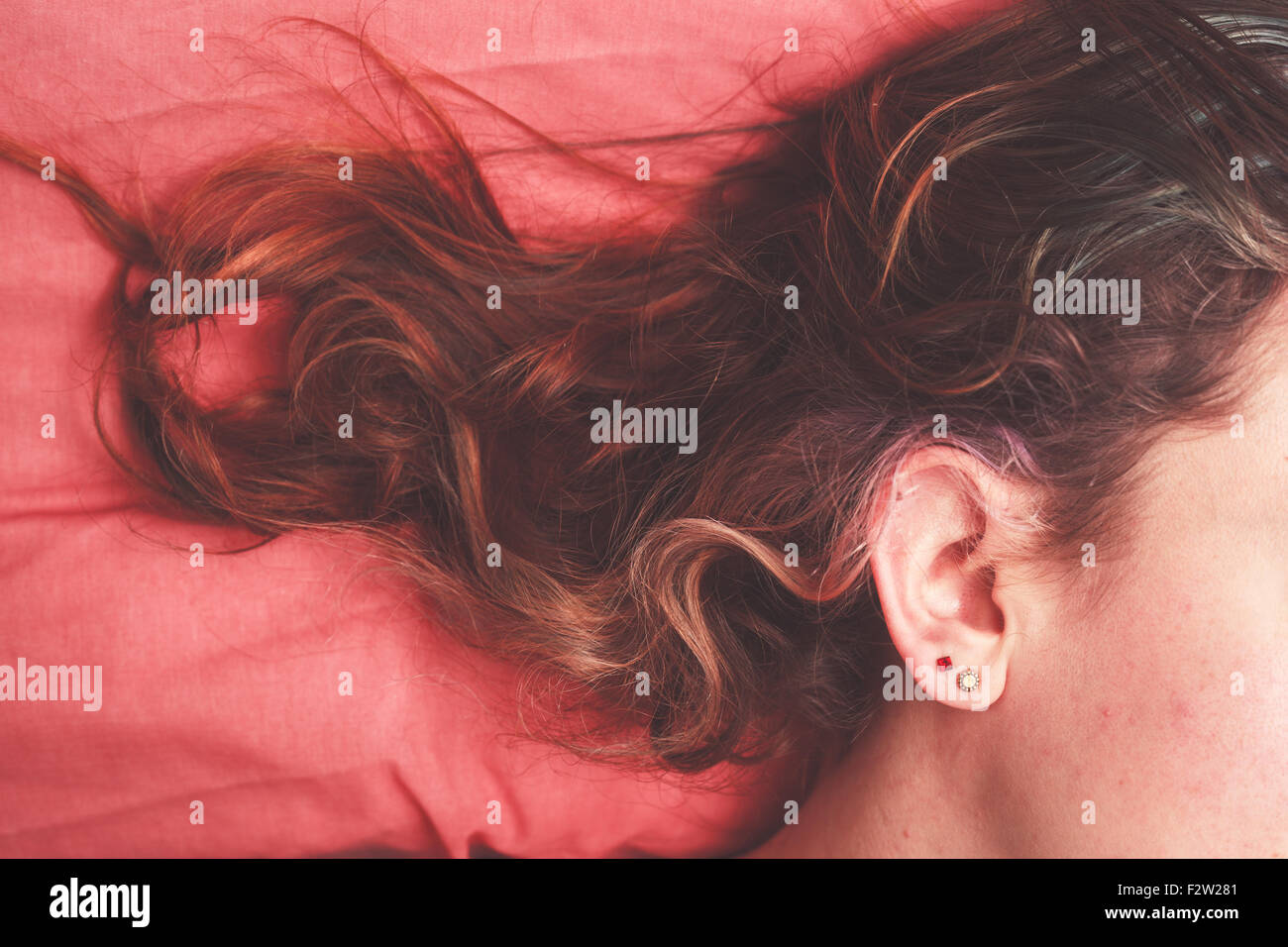 Jeune femme au lit avec ses cheveux éparpillés sur l'oreiller Banque D'Images