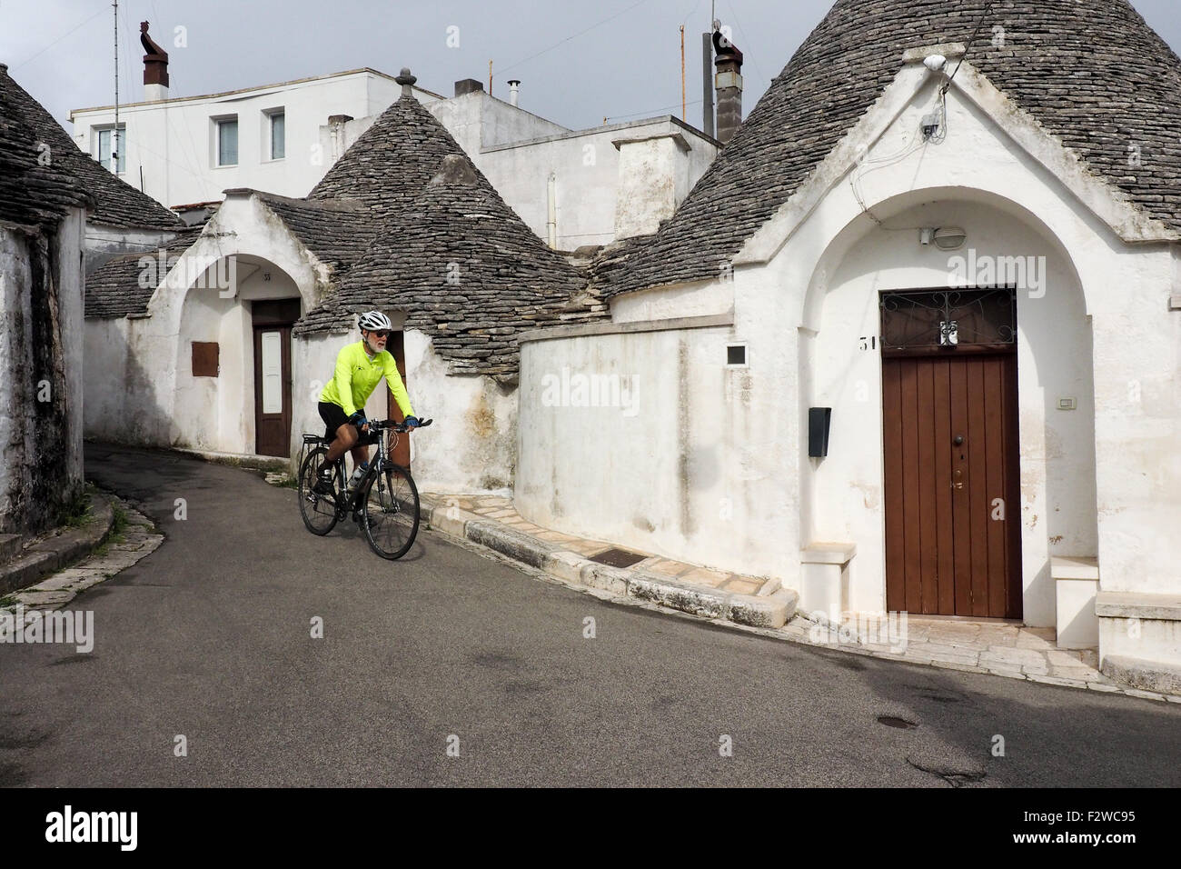 Randonnée vélo cycliste sur une rue de Trulli dans le quartier de Monti à Alberobello. Banque D'Images