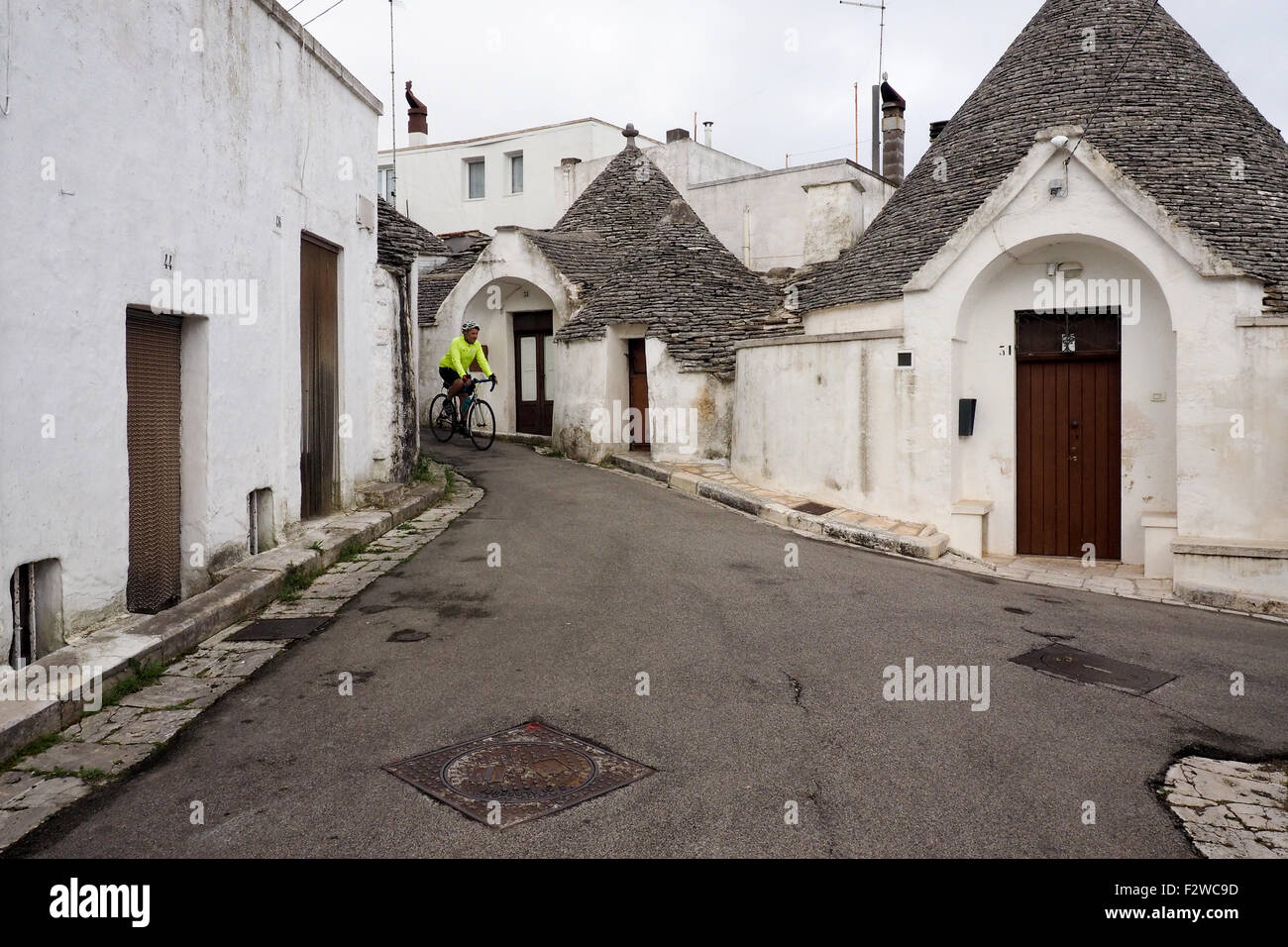 Randonnée vélo cycliste sur une rue de Trulli dans le quartier de Monti à Alberobello. Banque D'Images