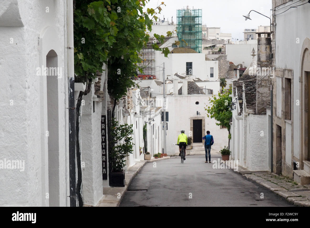 Un cycliste et piéton sur une rue de Trulli dans le quartier de Monti à Alberobello. Banque D'Images
