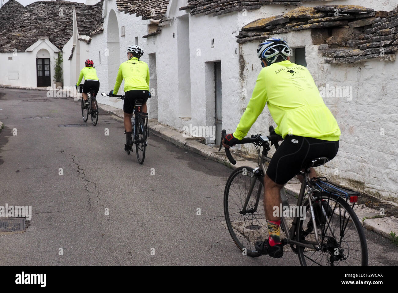 Trois des cyclotouristes du vélo dans une rue de Trulli dans le quartier de Monti à Alberobello. Banque D'Images