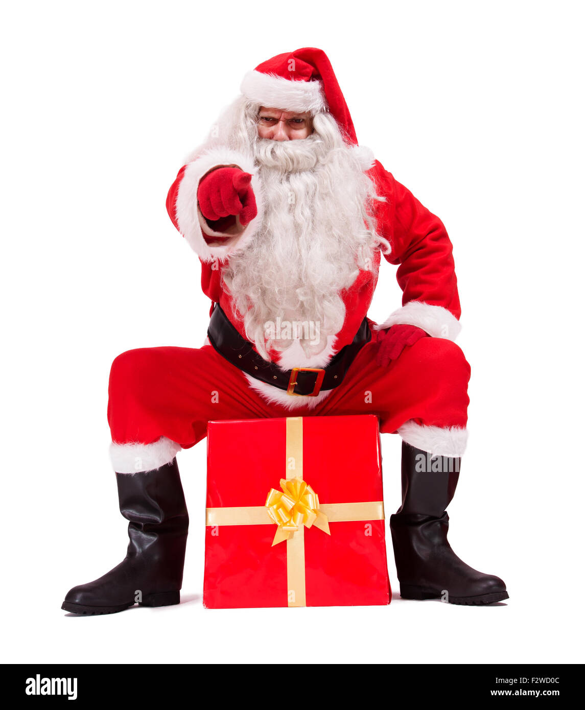 Père Noël assis sur cadeau et en pointant son doigt vers vous Banque D'Images
