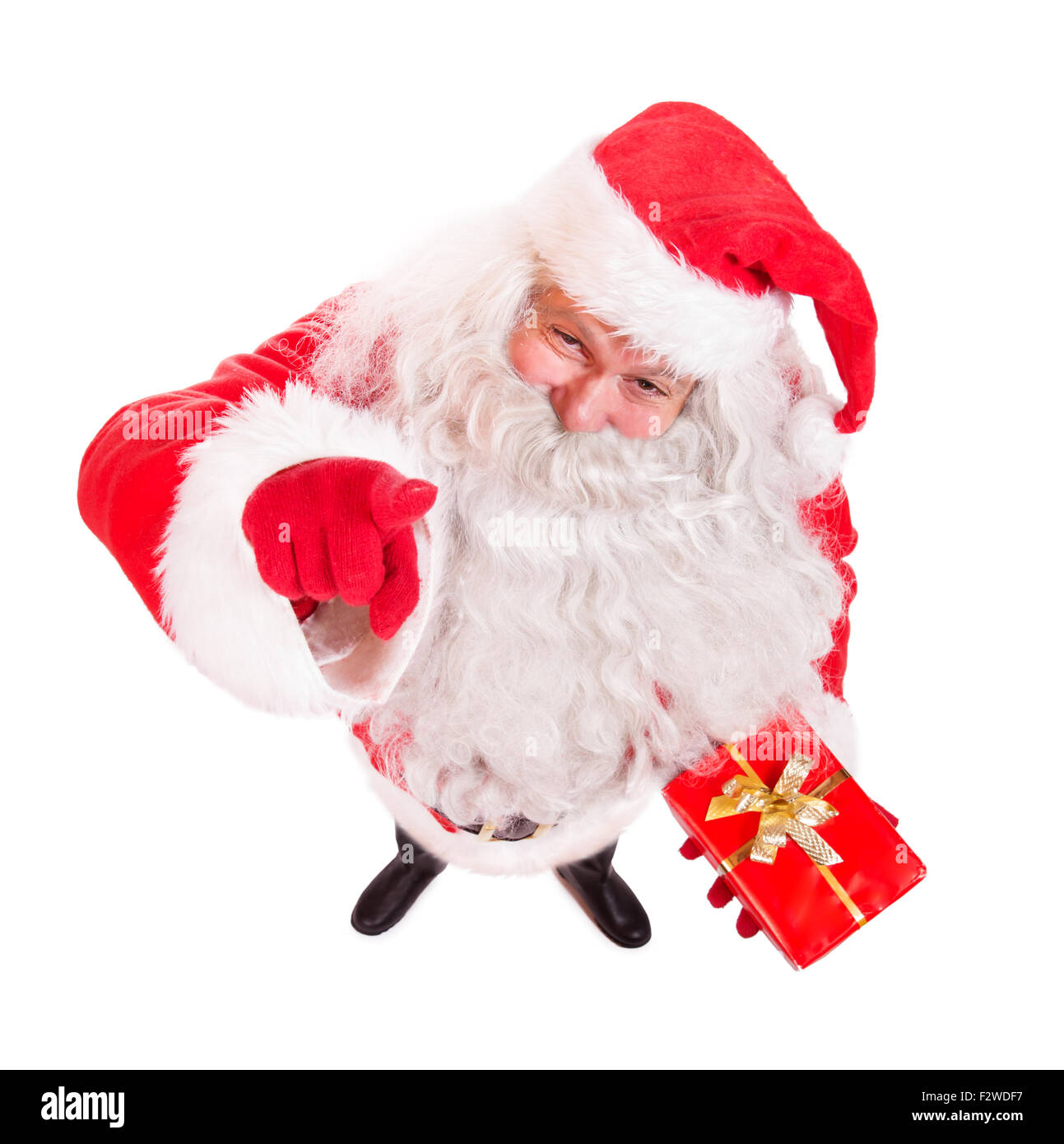 Le Père Noël avec un cadeau et pointant vers le haut à l'appareil photo Banque D'Images