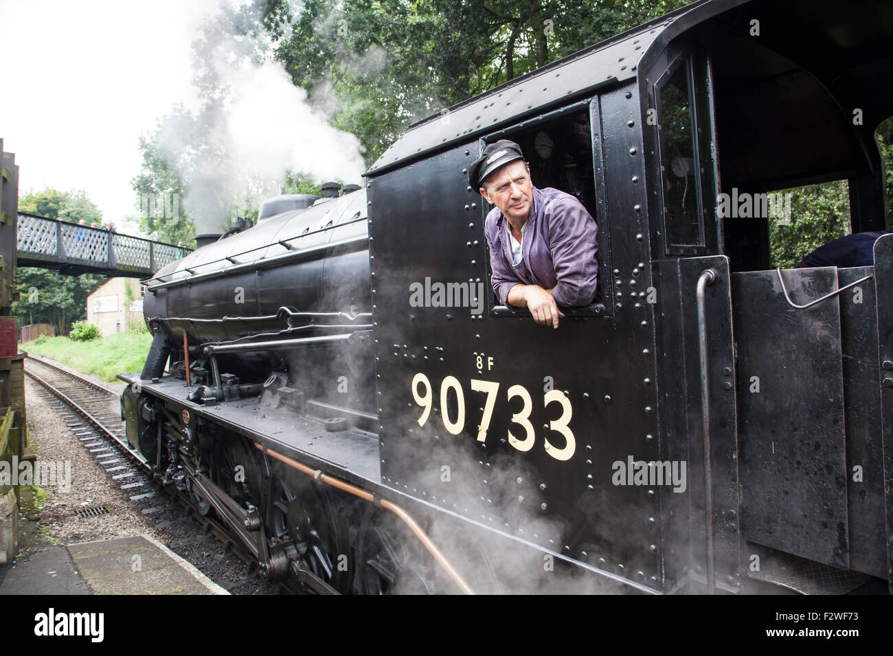 Le pilote du moteur de locomotive à vapeur, ingénieur conducteur de train dans la cabine d'austérité 90733 RM 2-8-0 à une station Banque D'Images