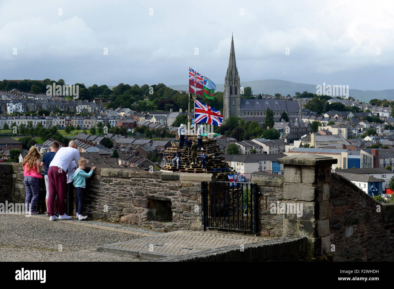 Les touristes en regardant les murs de Derry jeunes nationalistes debout sur un grand feu fait à partir de palettes en bois, dans le Bogside, Londres Banque D'Images