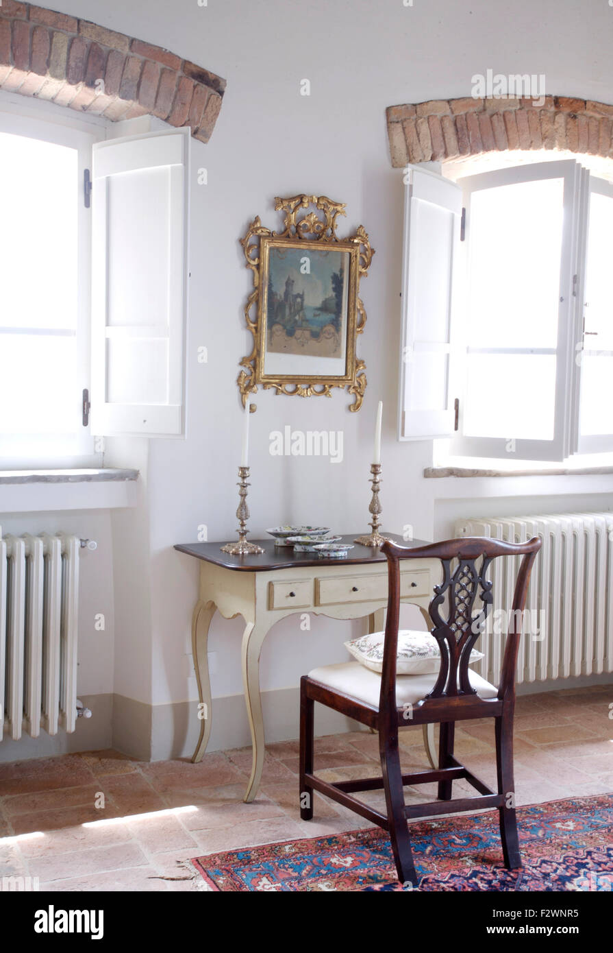 Le GILT image encadrée au-dessus de petite coiffeuse antique avec l'argent des chandeliers et chaise ancienne en italien chambres Banque D'Images