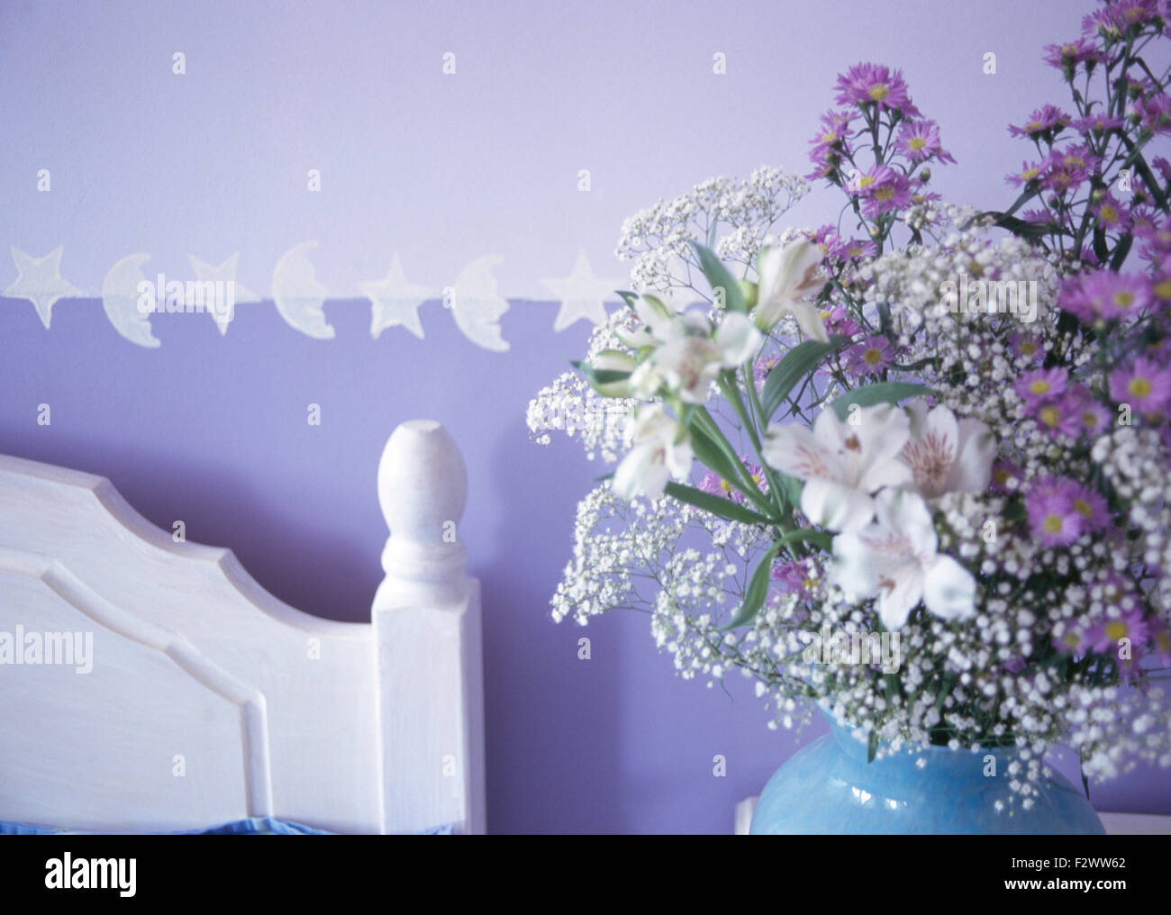 Close-up de vase de fleurs d'été à côté de la tête de lit blanc mauve dans 90 chambres Banque D'Images